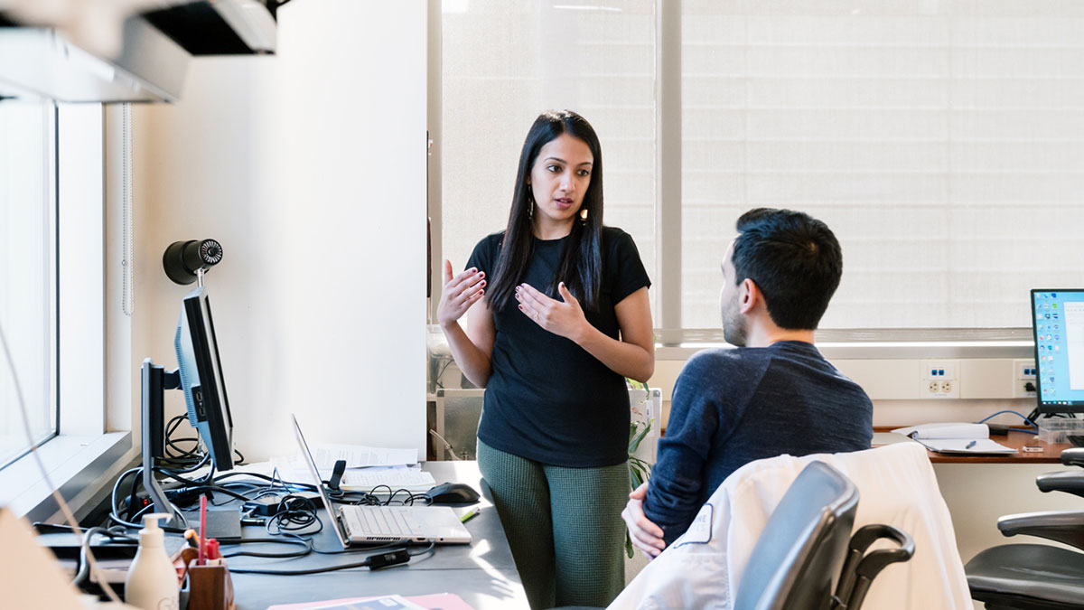 Isha Jain and Skyler Blume talking in a laboratory
